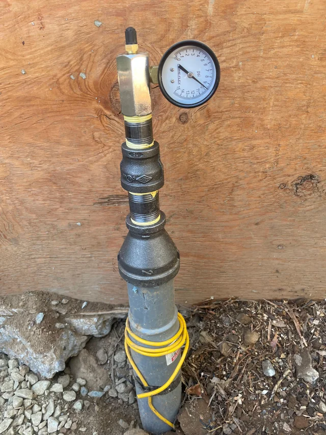Pressure gauge attached to a pipe in ground.